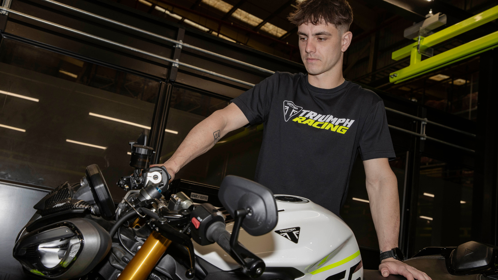 Man holding a Triumph Motorcycle wearing a black racing t-shirt