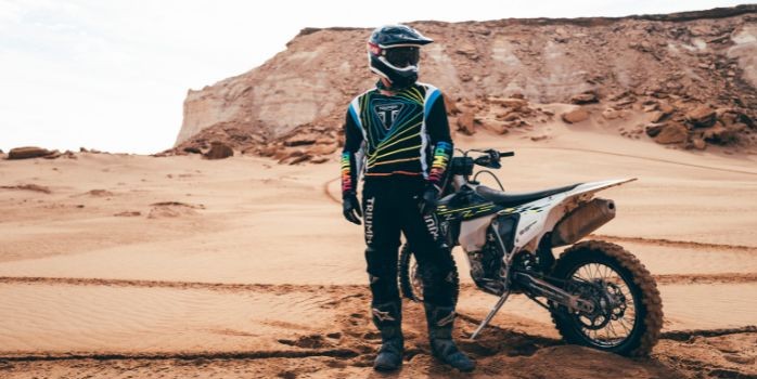 Man stood near bike in the desert wearing a Triumph Jersey